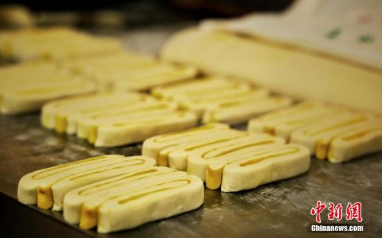 圖為面劑被涂上胡麻油，切成條狀用作月餅的花型制作。張文 攝