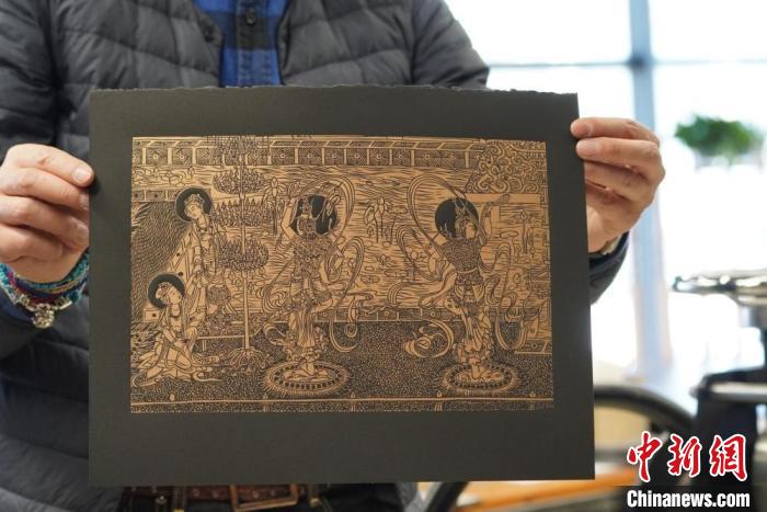 圖為手工書藝人展示敦煌雕版壁畫印刷品。　九美旦增 　攝