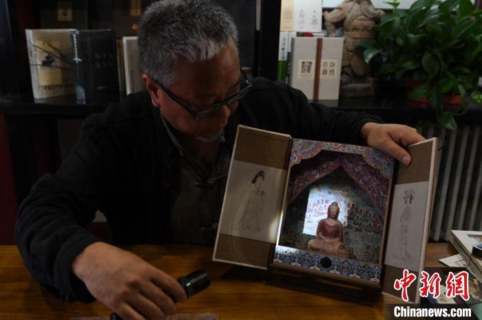圖為讀者出版集團(tuán)讀者晉林工作室獨(dú)立出品人徐晉林，展示互動(dòng)性強(qiáng)的敦煌題材手工書。(資料圖) 楊艷敏 攝