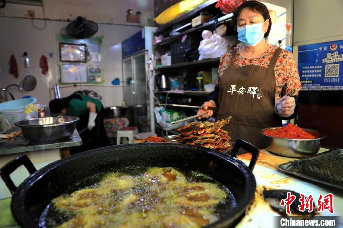圖為平安驛·河湟民俗文化體驗(yàn)地內(nèi)的商戶炸干板魚?！⊙Φ?攝