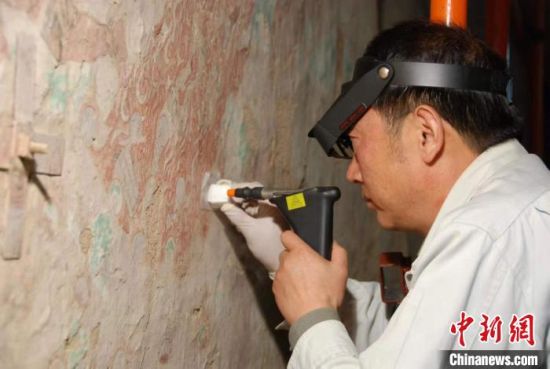 敦煌研究院研究員樊再軒進行壁畫修復。(資料圖)張云文 攝